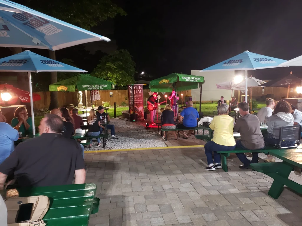 Outdoor restaurant patio at night, lively with patrons and live music.