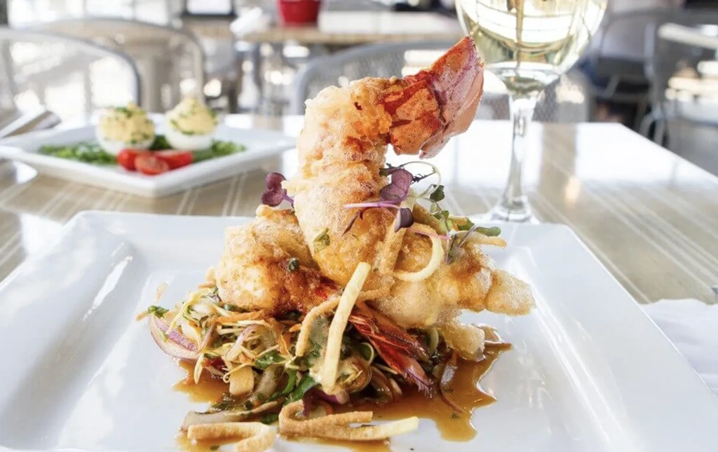 Crispy fried lobster tail on greens, with deviled eggs and wine.