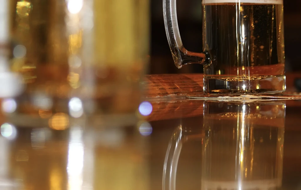 Golden beer mug with frothy head and condensation, another out of focus.
