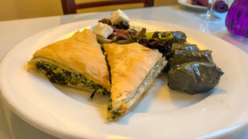 Appetizer plate with spanakopita, salad, and dolmades.