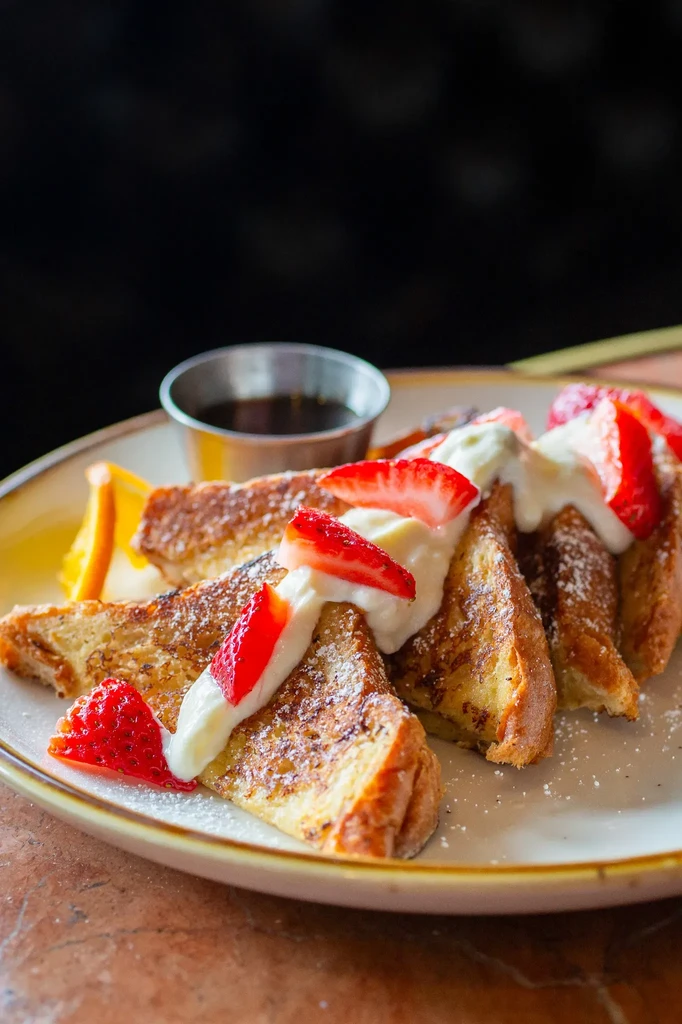 French toast topped with strawberries, whipped cream, and powdered sugar.