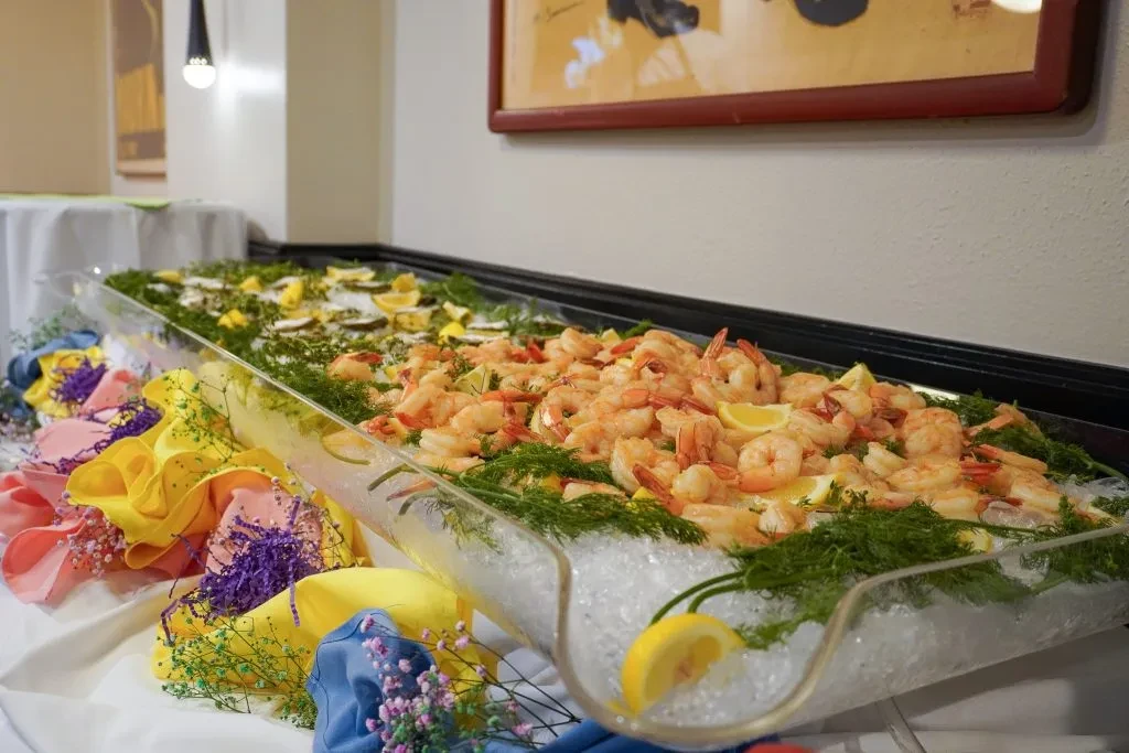 Shrimp cocktail and oysters on ice with lemon at a buffet.