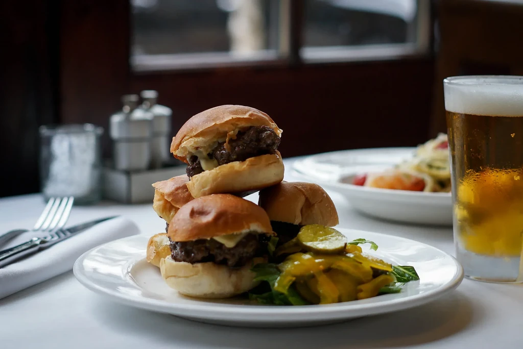 Stack of five sliders, pickles, and a chilled beer.
