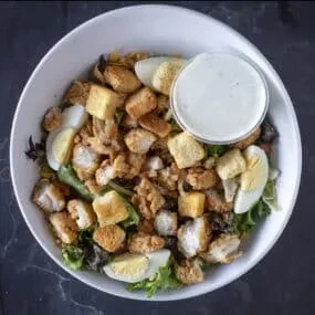 Overhead shot of chicken salad with egg, croutons, and creamy dressing.
