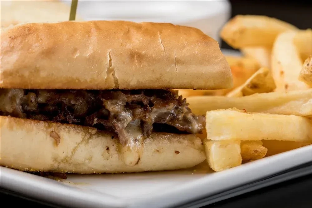 Shredded meat and melted cheese sandwich with a side of fries.