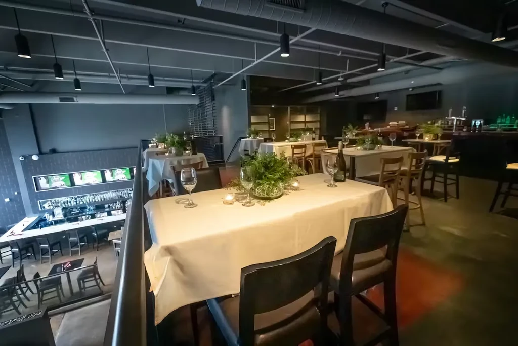 Multi-level restaurant interior with upscale dining tables, industrial decor, and sports bar.