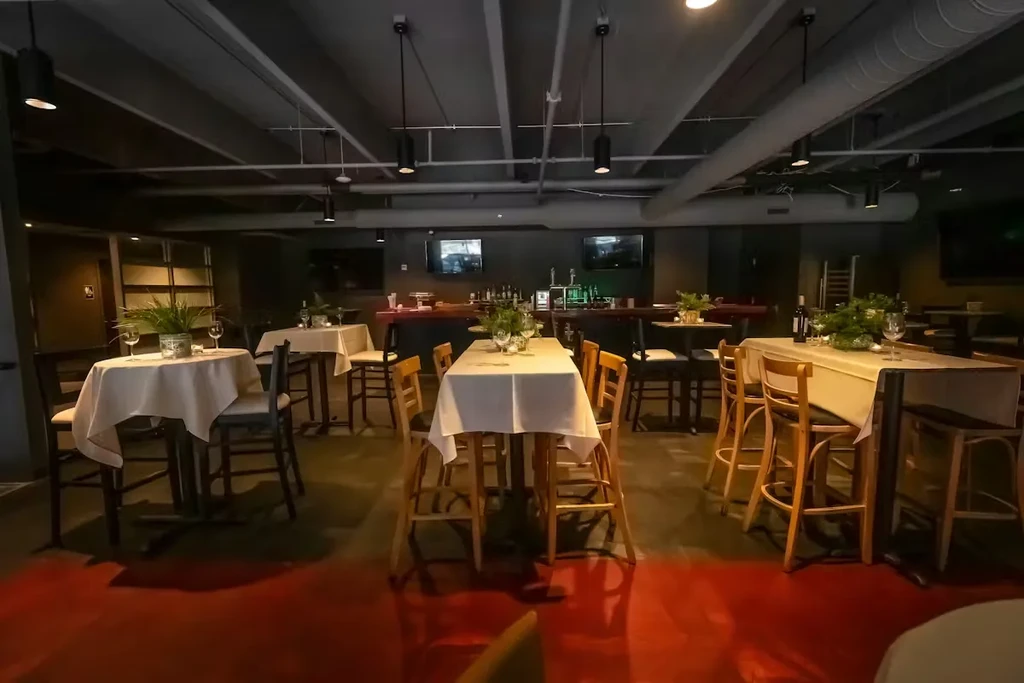 Dimly lit, empty modern restaurant bar with high-top tables.