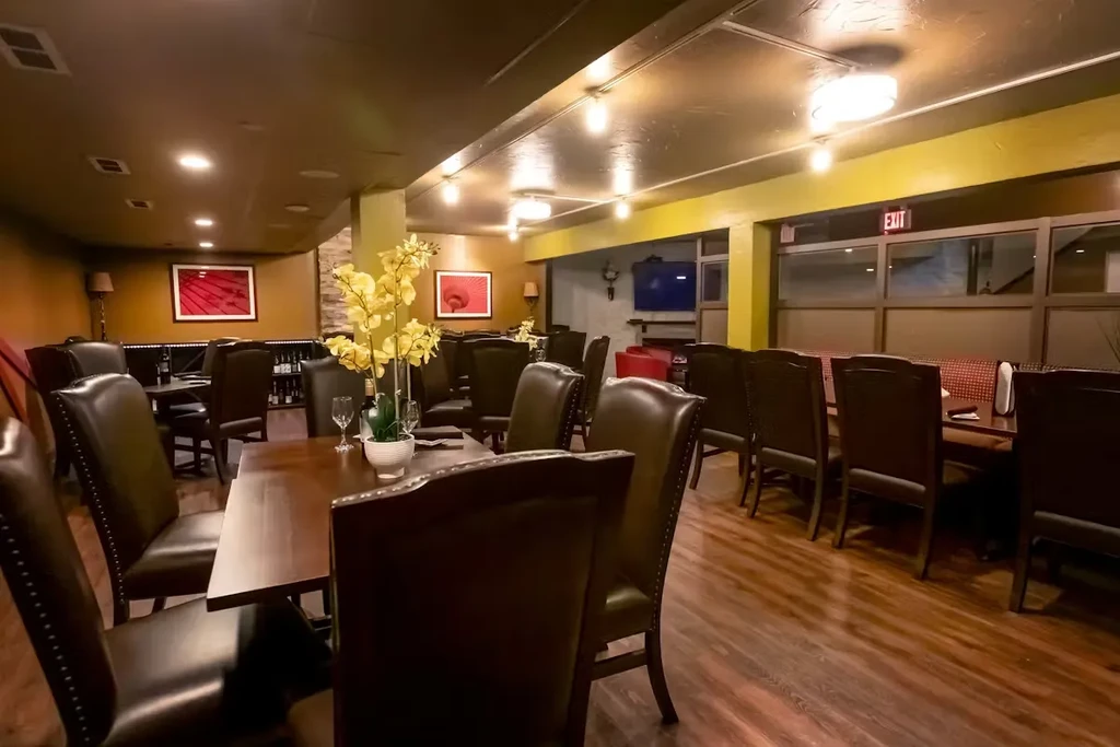 Empty restaurant interior with dark wood furniture and warm lighting.