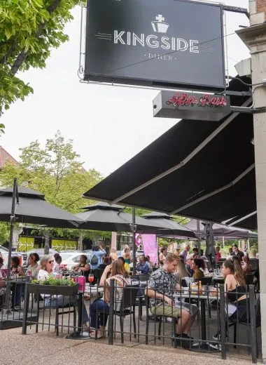 Kingside Diner outdoor patio bustling with patrons under black umbrellas.