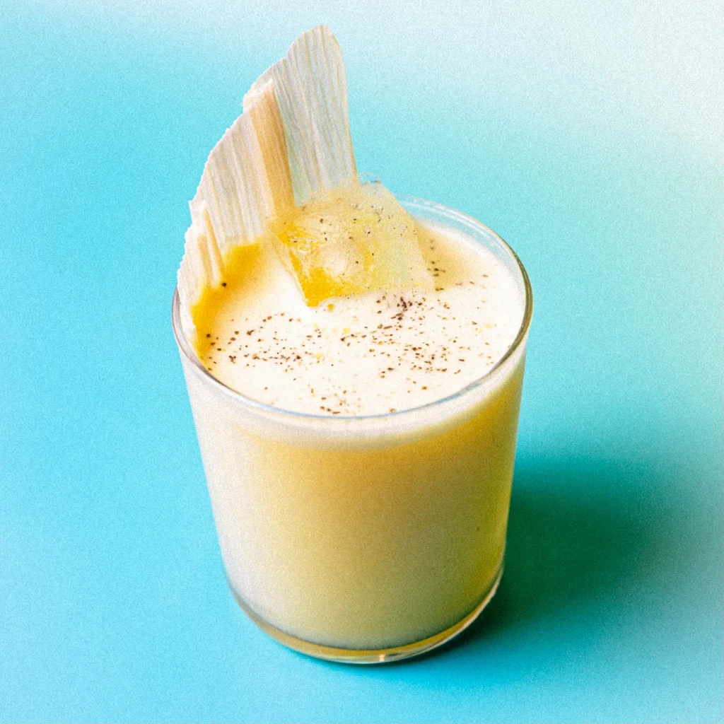 Frothy yellow drink, spiced, with translucent strip and jelly garnishes.