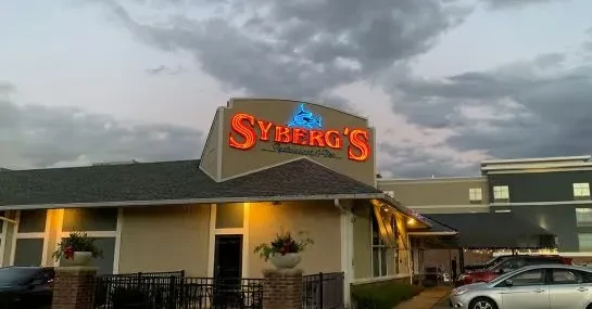 SYBERG'S Restaurant exterior at dusk, prominent neon sign with fish silhouette.
