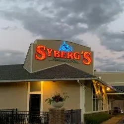 Exterior of Syberg's Restaurant & Bar building with neon sign at dusk.
