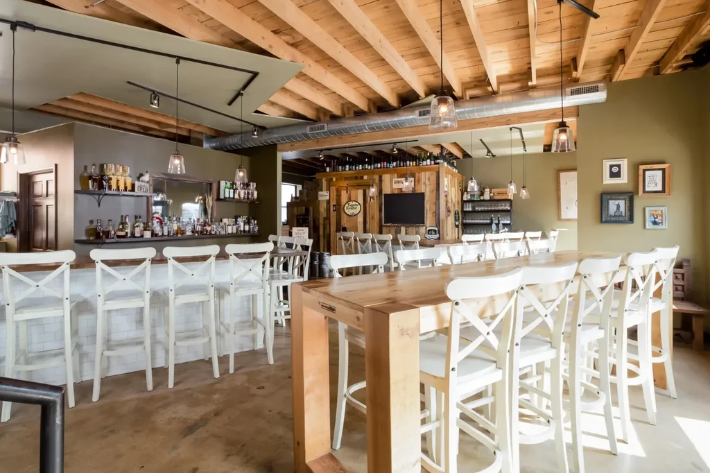 Modern rustic restaurant interior with bar, communal table, and X-back chairs.
