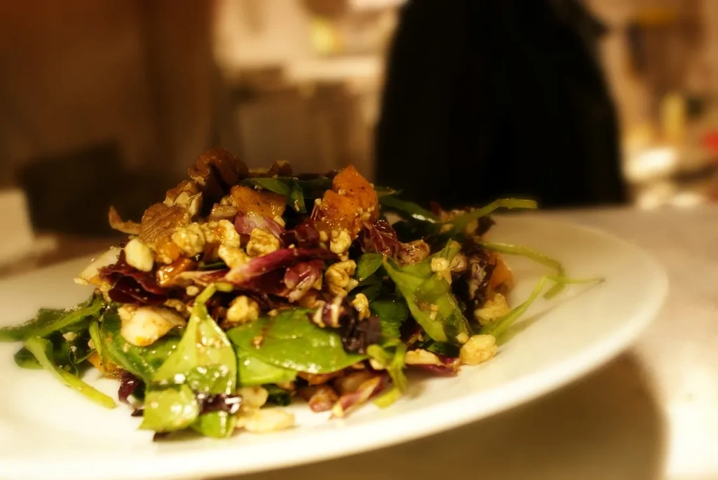 Close-up of a vibrant salad with greens, radicchio, squash, and nuts.