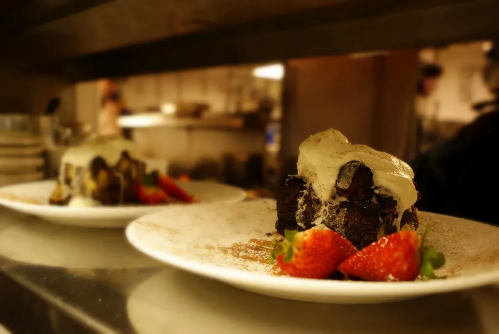 Two plated chocolate desserts with cream, strawberries, and powdered sugar.