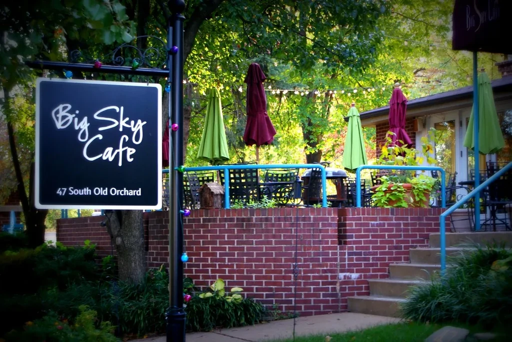 Big Sky Cafe sign, empty patio with green and red umbrellas.