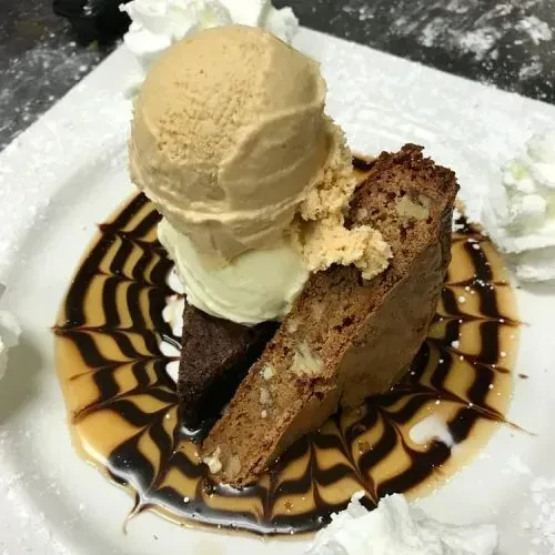 Chocolate cake, biscotti, two ice cream scoops, sauces, whipped cream.