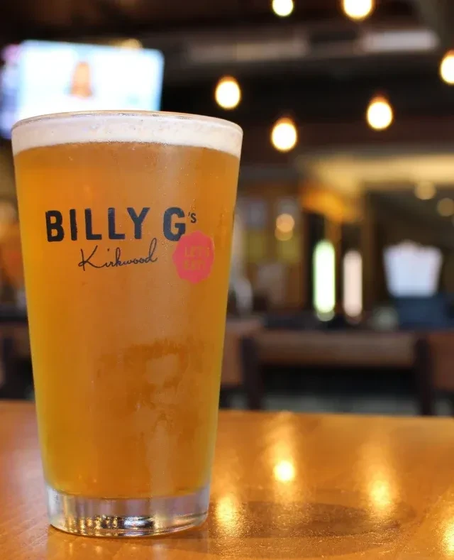 Frosty beer branded 'BILLY G's Kirkwood' on a wooden table.
