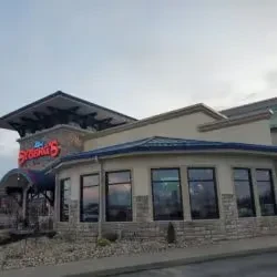 Modern restaurant building, "The Sycamore 5" sign, under cloudy sky.