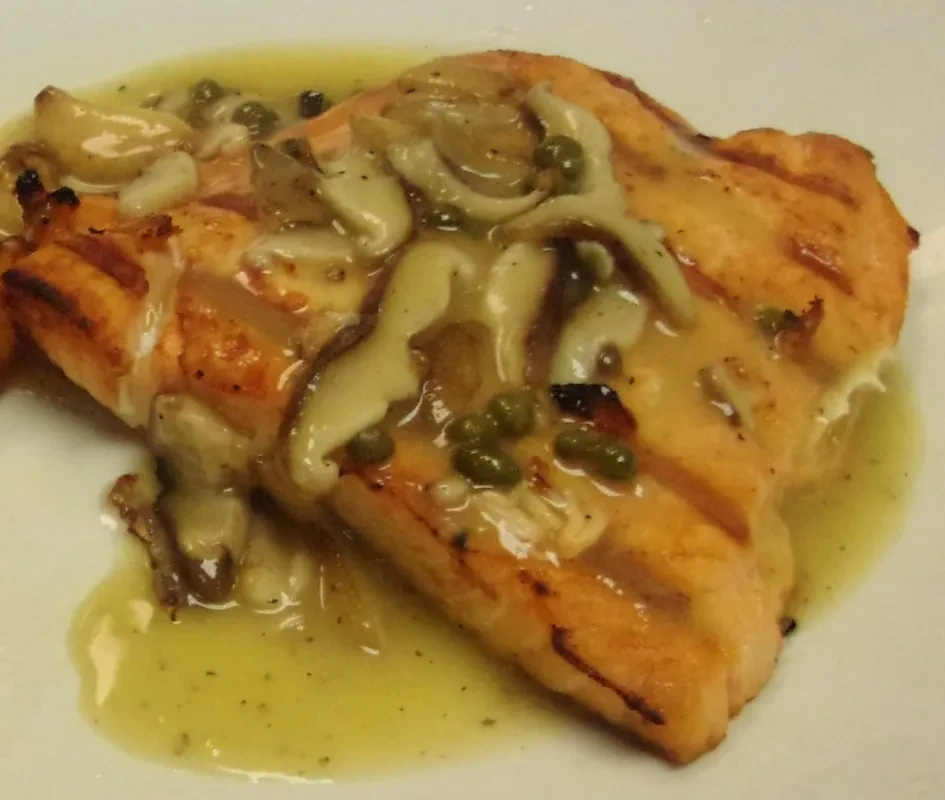 Grilled salmon with creamy lemon-butter sauce, mushrooms, and capers.