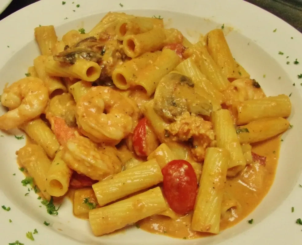 Overhead view of creamy pasta with shrimp, mushrooms, and tomatoes.