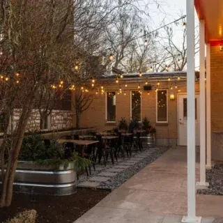 Nighttime restaurant patio with string lights, bare tree, and seating.