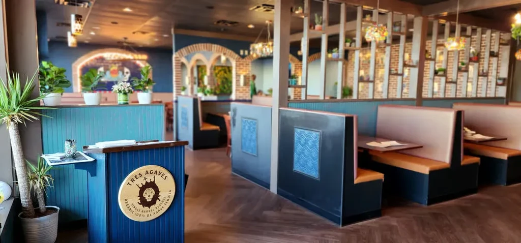 Modern restaurant interior with a Tres Agaves host stand and booth seating.