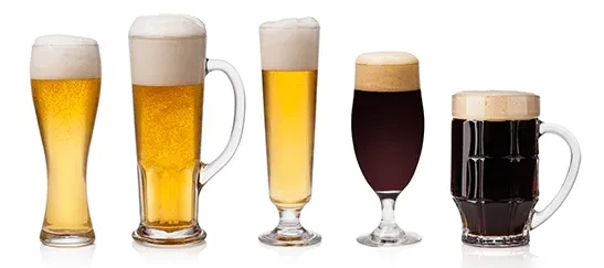Five distinct glasses of golden and dark beers on white.