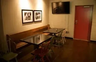 Dimly lit restaurant with wooden booth, tables, colorful chairs, and a red door.