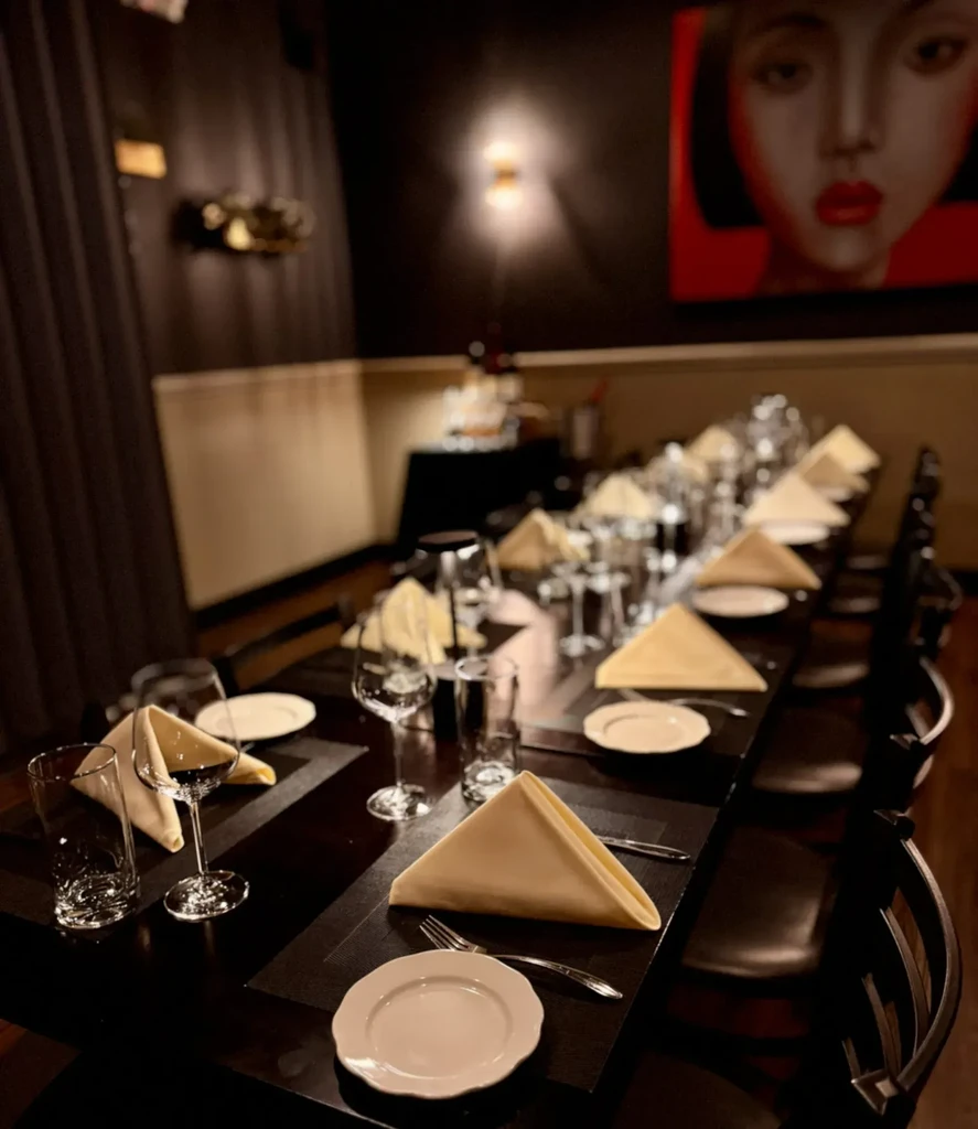Elegant dark dining table set for many, with stylized red artwork.