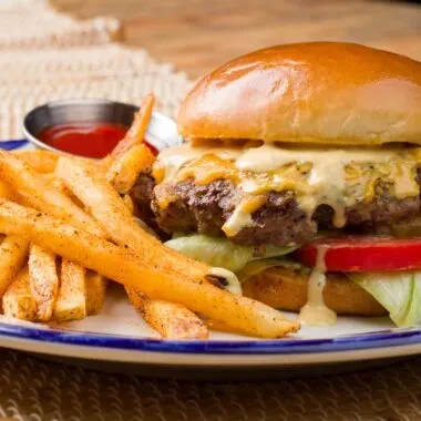 Cheeseburger with melted cheese, crispy fries, and ketchup on a plate.