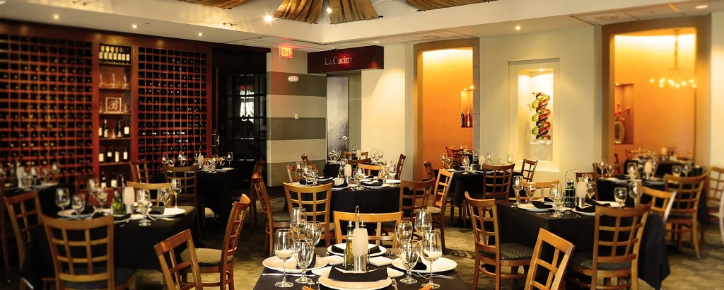 La Cucina restaurant dining area, set tables, large wooden wine rack.