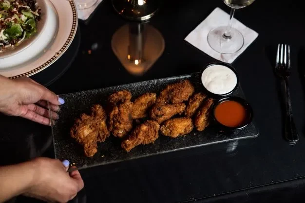 Golden fried chicken wings, two sauces, salad, and white wine.