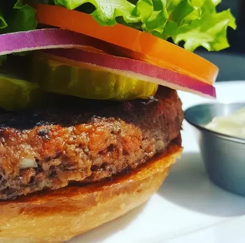 Close-up of a well-presented burger with thick patty and fresh toppings.