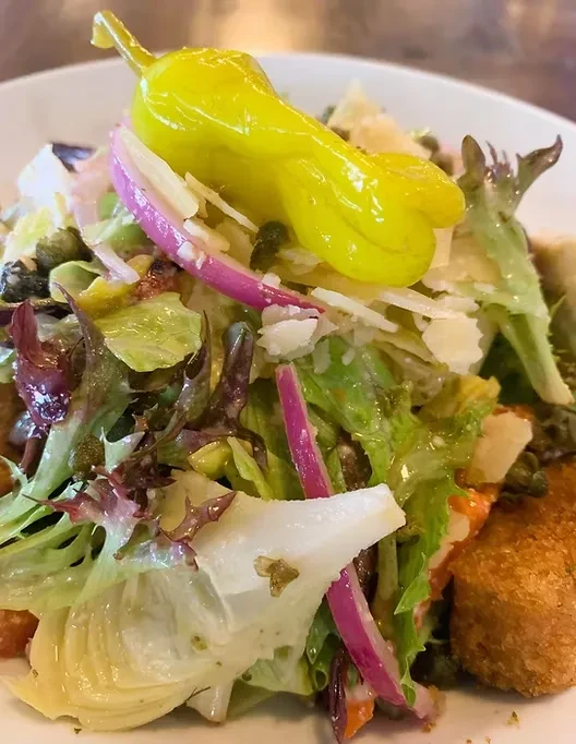 Colorful salad with Parmesan, pepperoncini, and fried food.