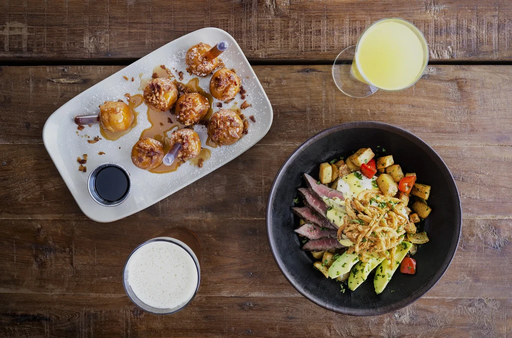 Overhead shot of caramel desserts, a steak bowl, and two drinks.