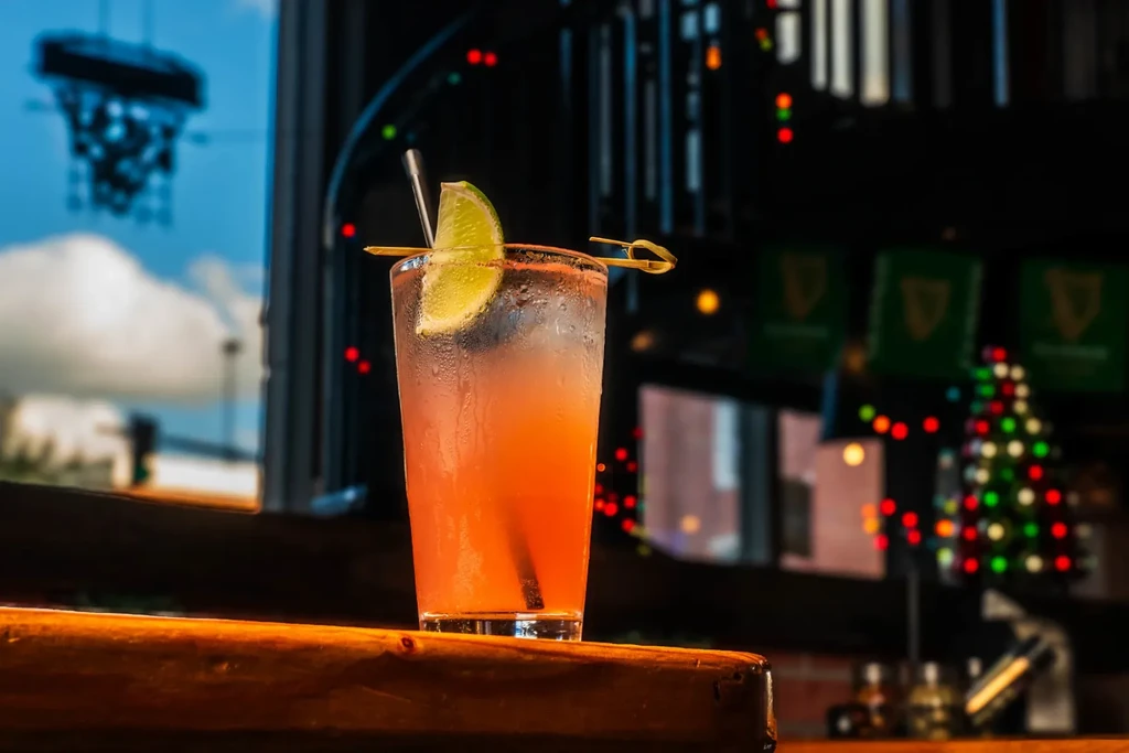 Frosty gradient beverage with lime and straw on a wooden bar.