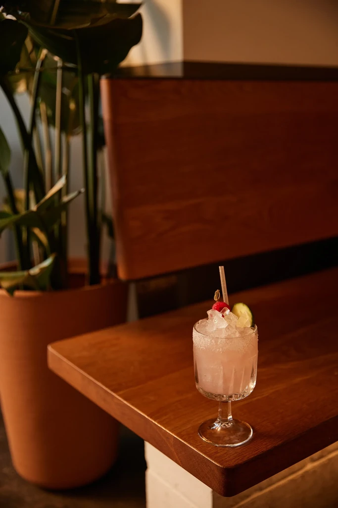 Frosted pink cocktail with crushed ice, red berries, and lime.