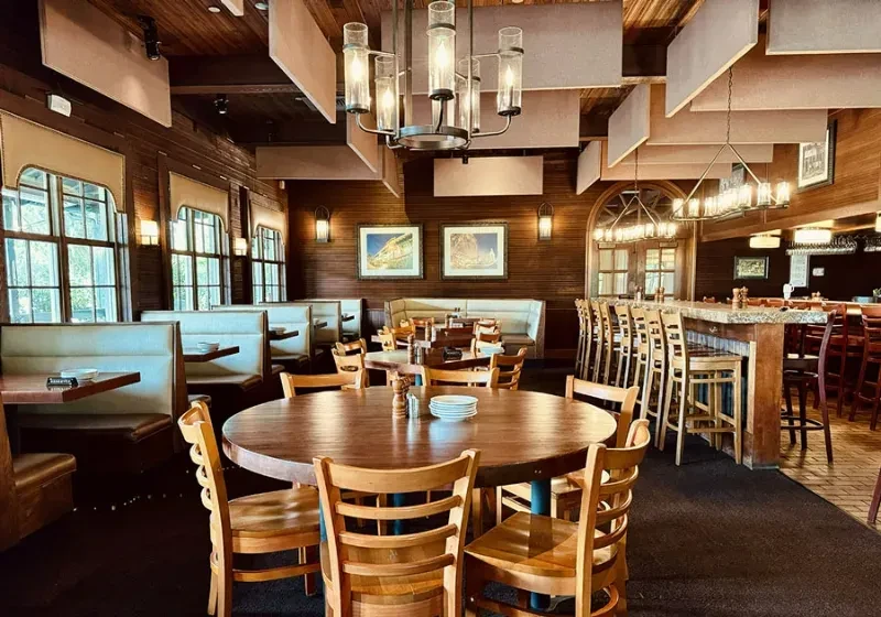 Rustic, elegant restaurant interior with booths, wooden tables, and a bar.