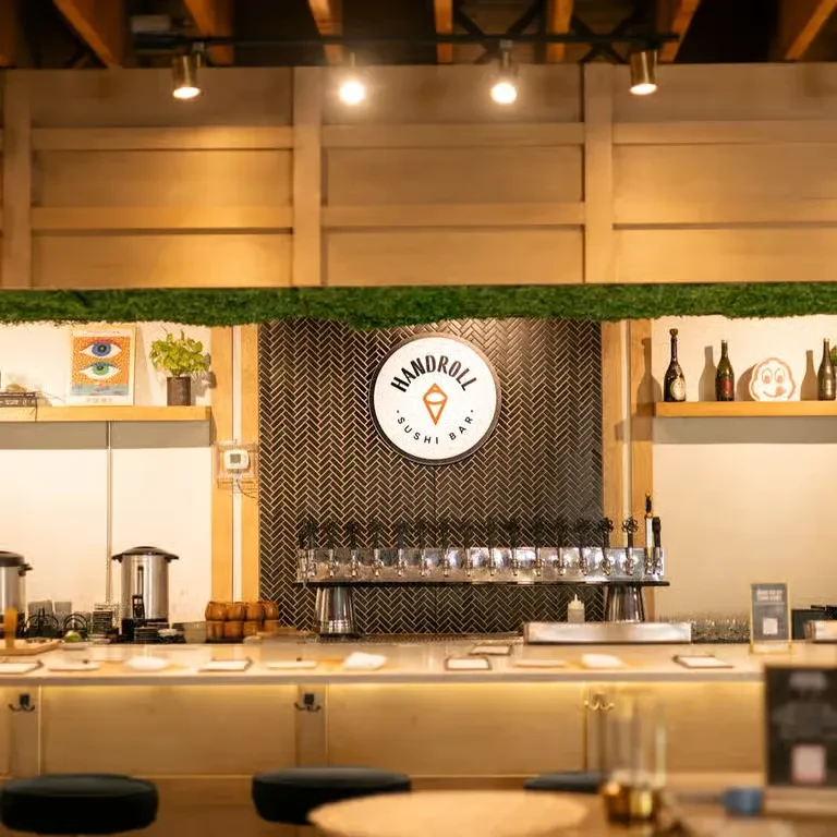 Modern sushi bar counter with black and gold herringbone tiled wall.