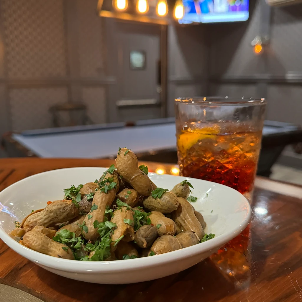 Boiled peanuts and an iced drink on a wooden pub table.