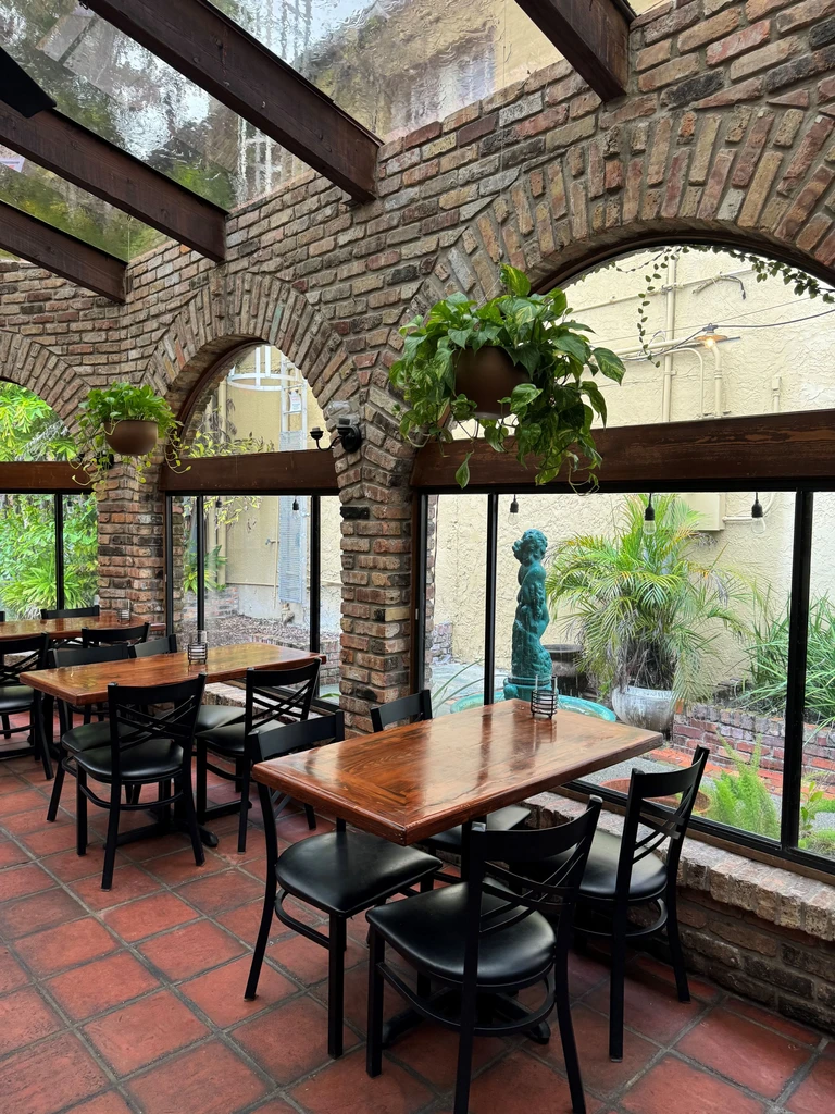 Bright, empty rustic cafe with brick arches and garden through windows.