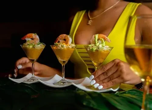 Three shrimp cocktails in martini glasses, one held by a person.