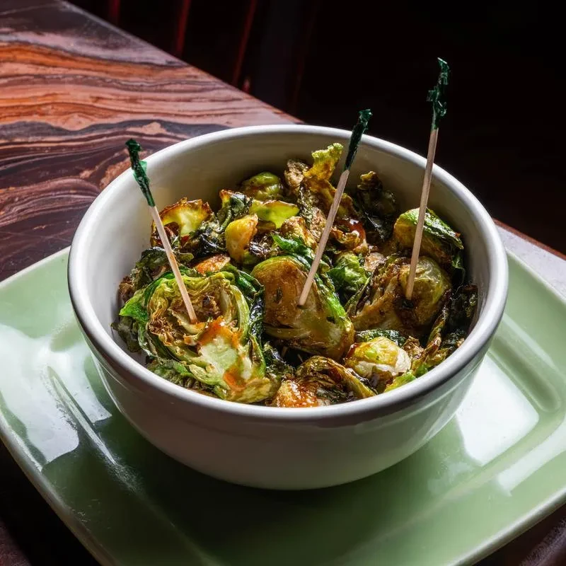 Roasted Brussels sprouts in a white bowl with decorative toothpicks.