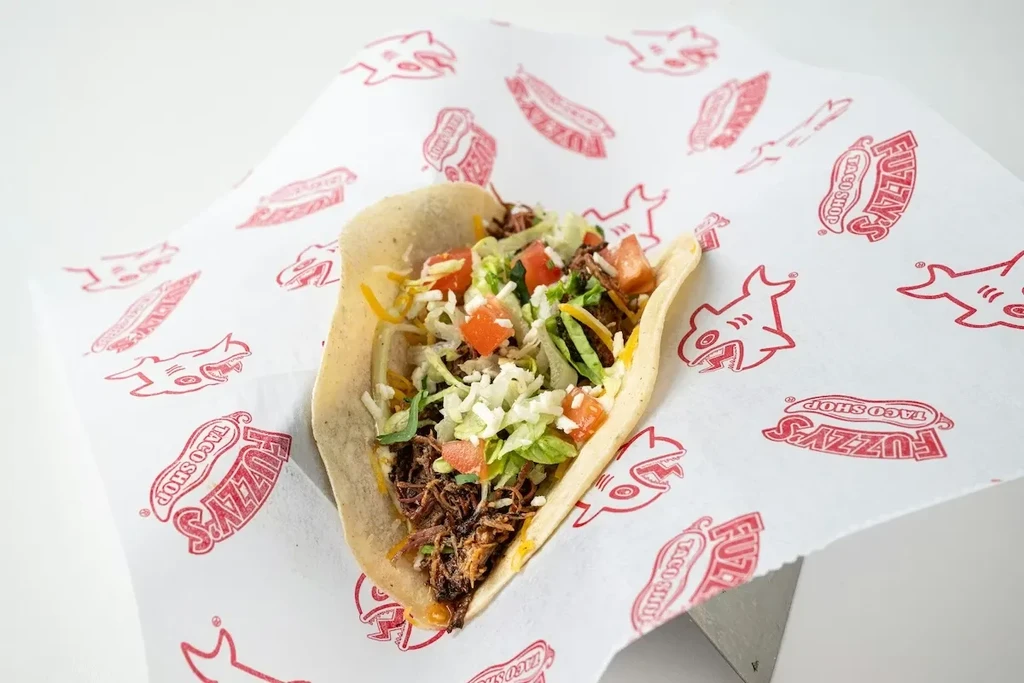 Fuzzy's Taco Shop taco, open, with meat, lettuce, tomato, cheese.
