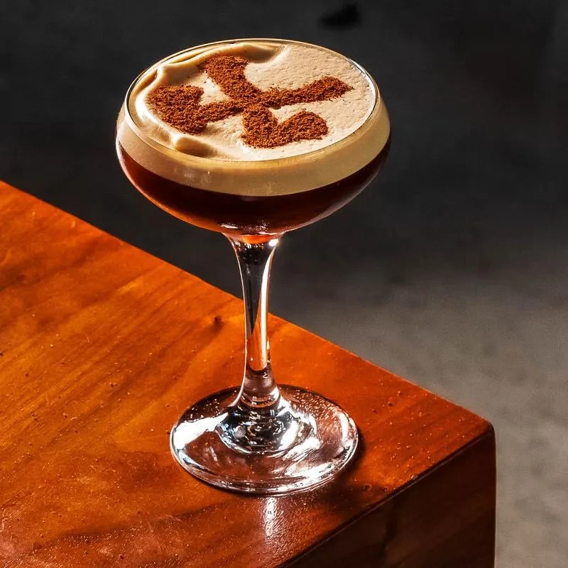 Espresso cocktail in coupe glass with creamy foam and dusted pattern.