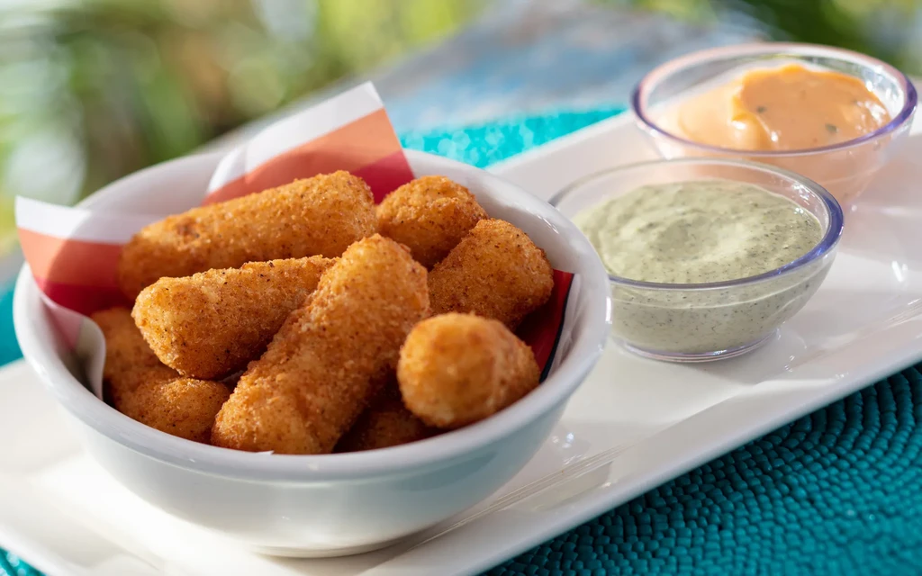 Bowl of golden fried food with two dipping sauces on a white tray.