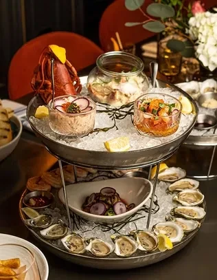 Multi-tiered seafood tower featuring lobster, oysters, and cold seafood.