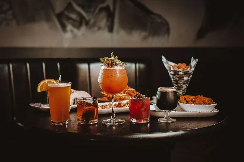 Assorted drinks and appetizers arranged on a dark wooden table.