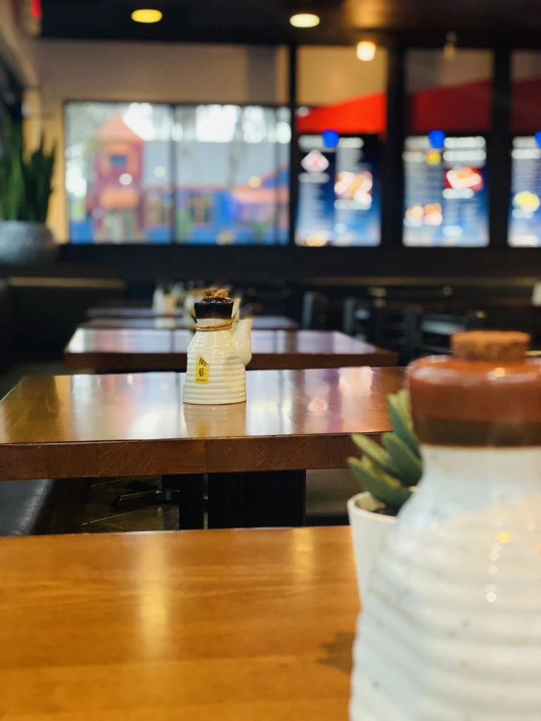Wooden tables with rustic Japanese condiment dispensers inside a restaurant.